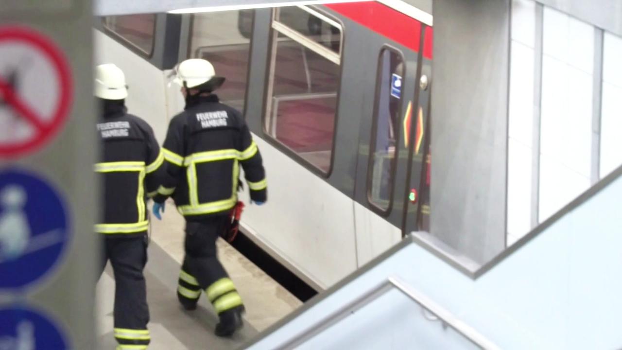 Einsatzkräfte der Feuerwehr gehen entlang eines Bahnsteigs.