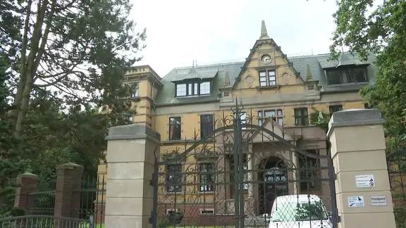 Das Bild zeigt eine Pforte und dahinter ein älteres Gutshaus in Jessenitz im Landkreis Ludwigslust-Parchim.