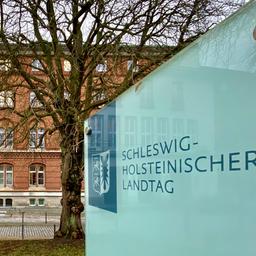 Ein großes Schild mit dem Schriftzug "Schleswig-Holsteinischer Landtag" steht vor dem Gebäude des Landeshauses in Kiel.