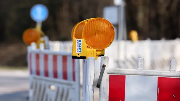Die Baustelle betrifft auch den ÖPNV. | NDR, Pavel Stoyan Auf einer Straße stehen mehrere Baustellenzäune, an denen gelbe Baustellenlampen angebracht sind.