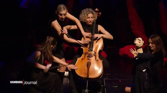 Das Frauenquartett "Salut Salon" steht auf der Bühne mit einem Cello und einer Holzpuppe.