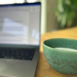 Aufgeklappter Laptop mit danebenstehender Tasse.