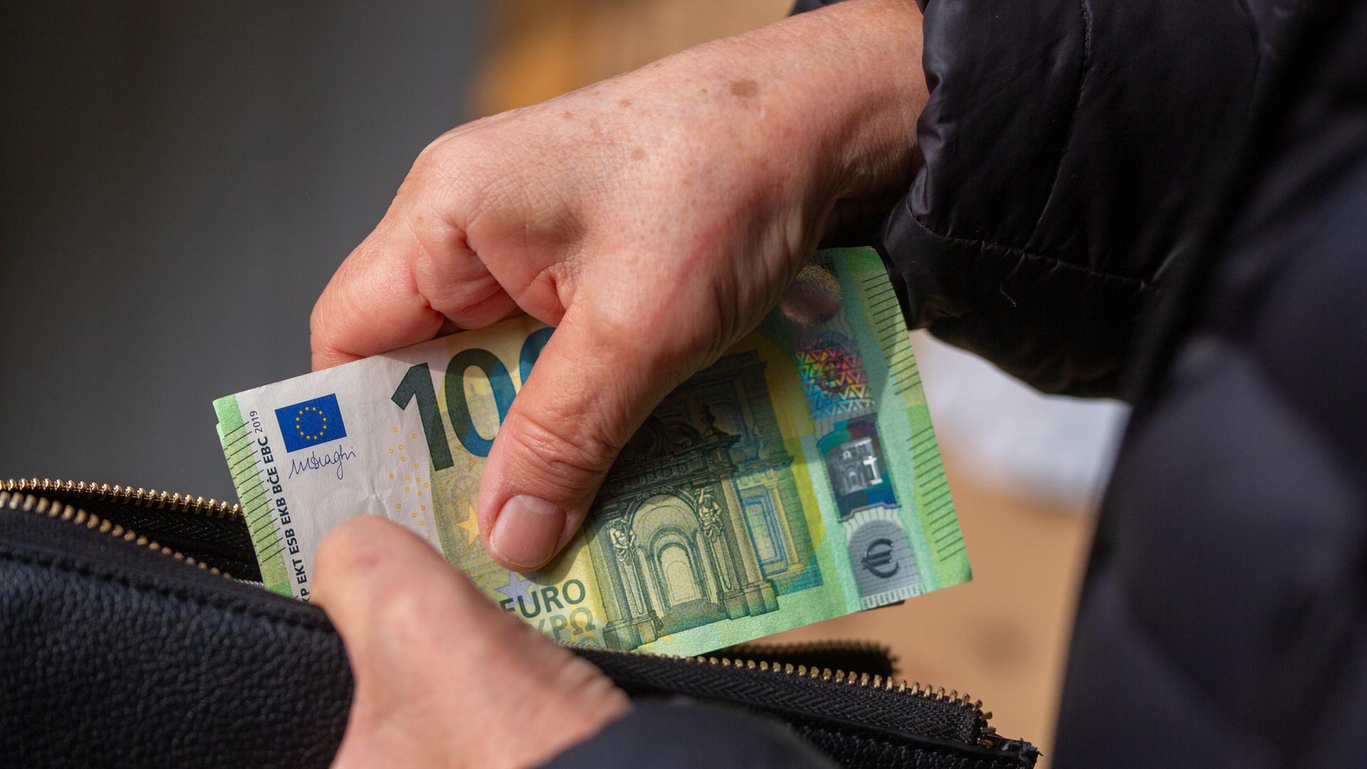 Eine Seniorin steckt Euro-Banknoten in eine Geldbörse. | picture alliance/dpa | Fernando Gutierrez-Juarez