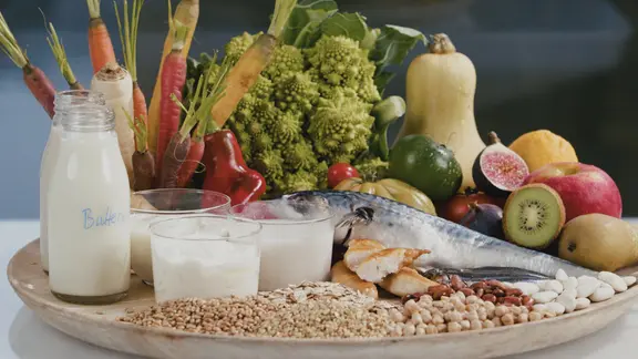 Eine große Platte mit schön arrangierten gesunden Lebensmitteln: Gemüse aller Art, Milchprodukte, Fisch, Getreide.