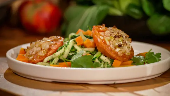 Zucchininudeln mit Karotten und Ofentomaten angerichtet auf einem Teller.