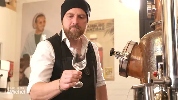 Hauke Günther schwenkt ein kleines Stielglas.