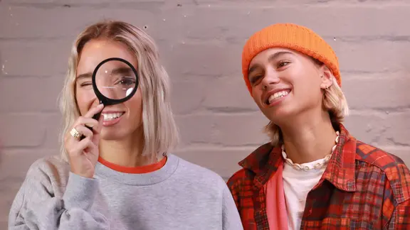 Lisa und Lena schauen durch eine Lupe.