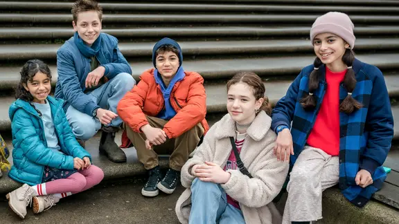 Die Pfefferkörner sitzen auf einer Treppe zum Gruppenfoto: Amy, Moritz, Hakim, Leo und Jasina.