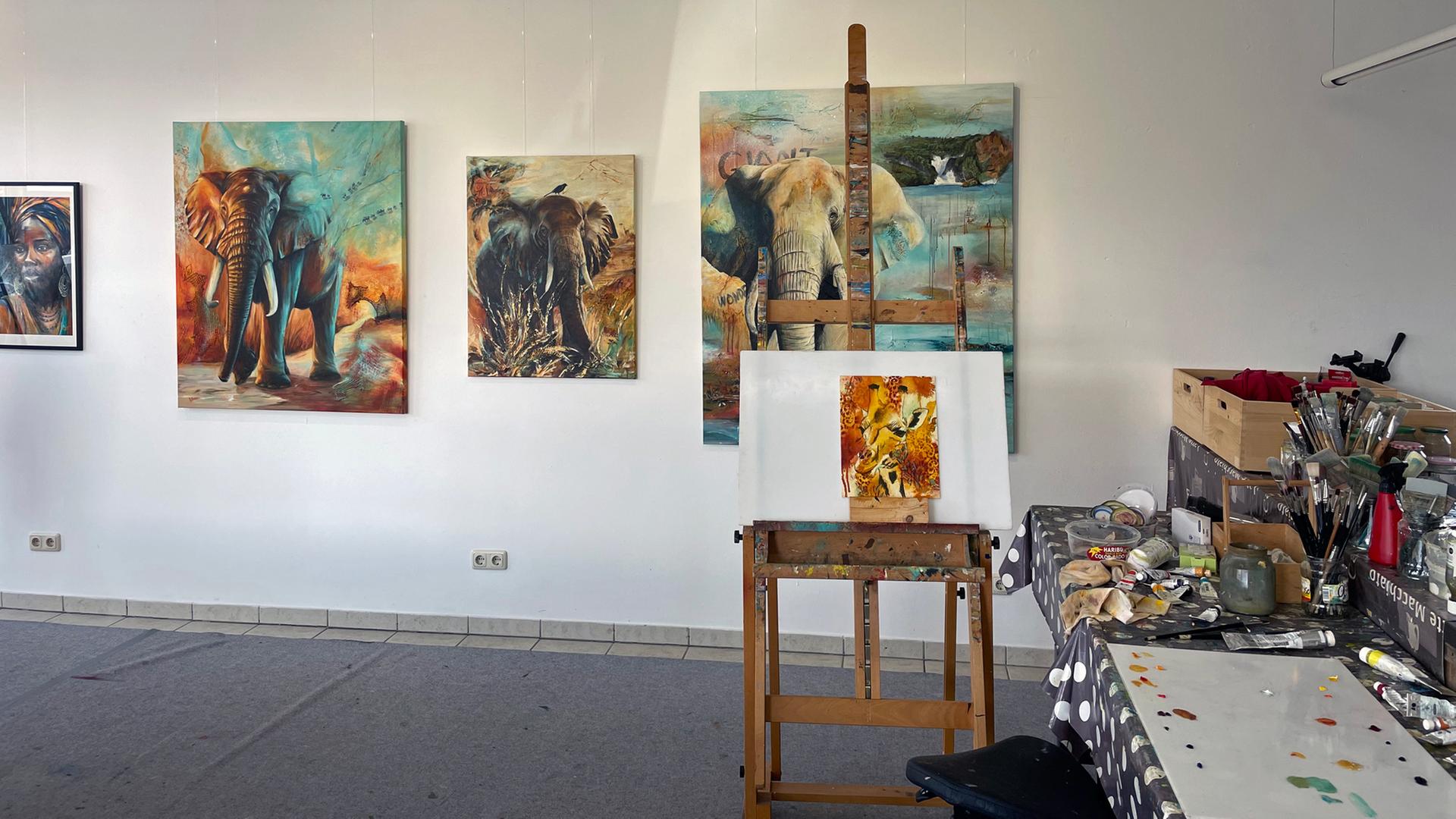 In einem Atelier hängen Bilder von Elefanten an der Wand; im Vordergrund steht eine Staffelei.  | NDR, Foto: Frank Hajasch