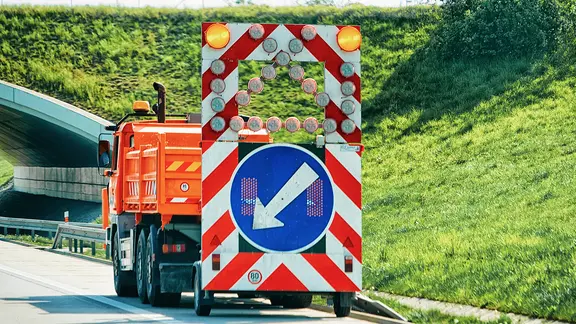 Ein Baustellen Fahrzeug auf der Standspur einer Autobahn.