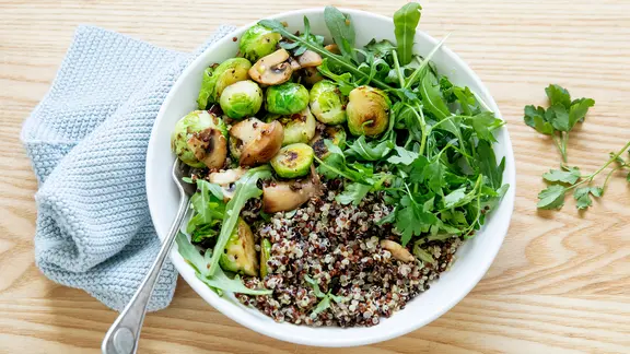 Eine Schale mit Quinoa, Pilzen, Rucola und Rosenkohl.