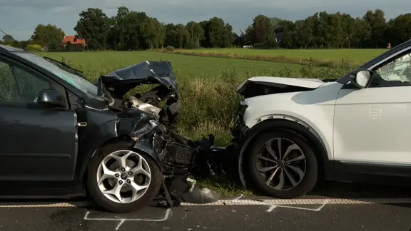 Nach einem Unfall stehen zwei beschädigte Autos auf der Straße.