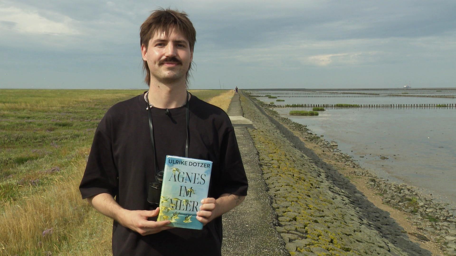Sam-Luke Ferrier hält das Buch