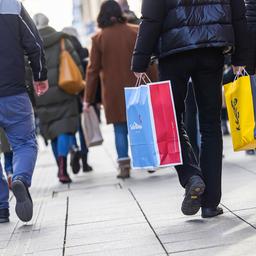 Menschen gehen mit Einkaufstüten durch eine Straße