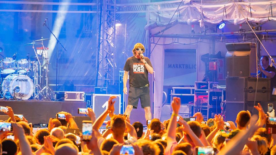 Schlägersänger Mickie Krause begeisterte am Freitagabend das Publikum auf dem Markplatz. | Stadt Lingen Mickie Krause steht mit Mikrofon auf einer Bühne und hat einen Auftritt, davor Publikum mit Handys in der Luft.