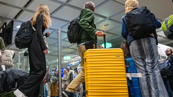 Reisende mit Koffern am Flughafen.