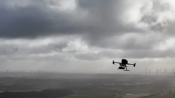 Eine fliegende Drohne vor grauen Wolken