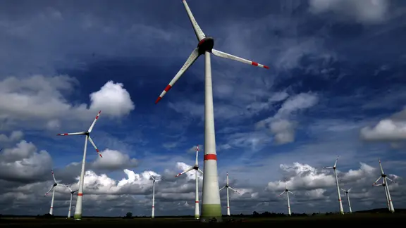 Altentreptow: Ein Windpark mit mehreren Windrädern zeichnet sich gegen den blauen, leicht bewölkten Himmel ab.