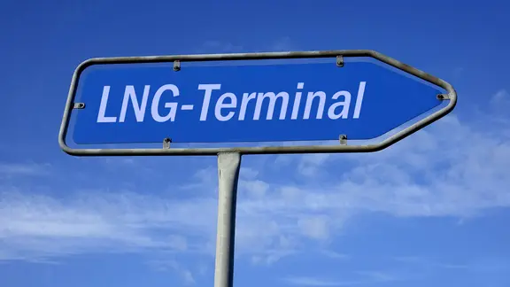 Auf einem Hinweisschild vor blauem Himmel steht "LNG-Terminal".