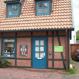 Blick auf eine kleinere blaue Tür in einem Fachwerkhaus in einer Fußgängerzone, daneben weist ein grünes Schild eine Gewaltschutz-Beratungsstelle aus.