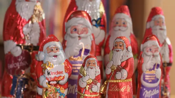 Mehrere Schokoladen-Weihnachtsmänner in bunter Folie stehen nebeneinander