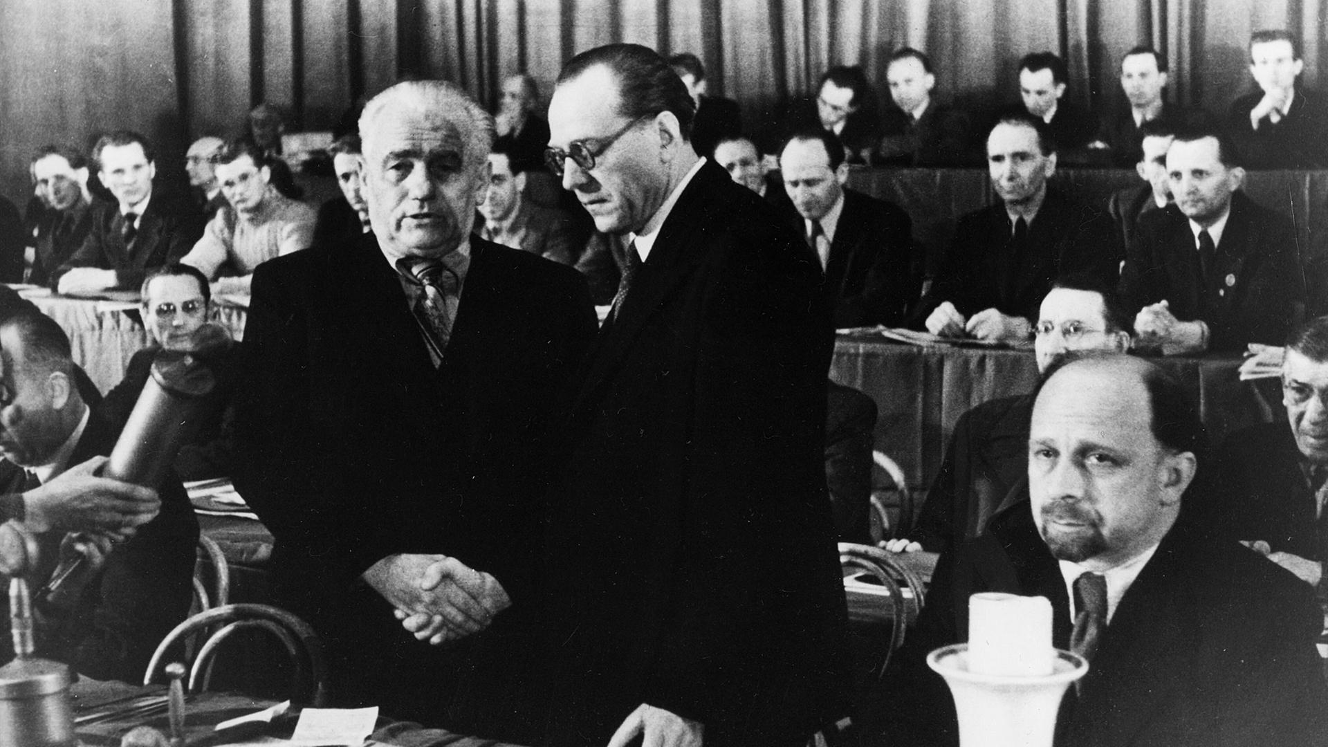Kommunist Wilhelm Pieck (l.) und Sozialdemokrat Otto Grotewohl besiegeln die Vereinigung von SPD und KPD am 22. April 1946 im Berliner Admiralspalast per Händedruck. | picture-alliance / akg-images , akg-images