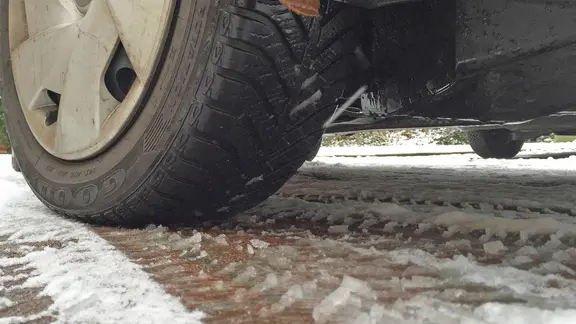 Ein Autoreifen rollt durch Schneematsch