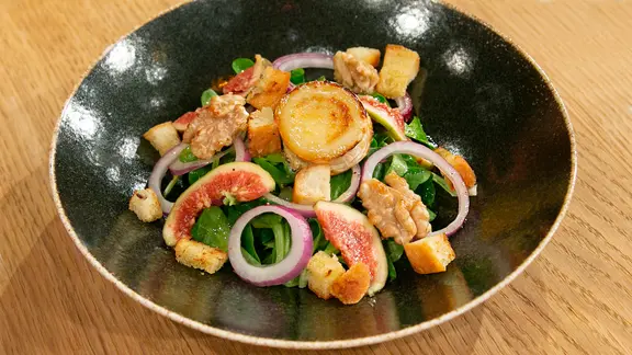 Feldsalat mit gratiniertem Ziegenkäse und Feigen auf einem Teller angerichtet.