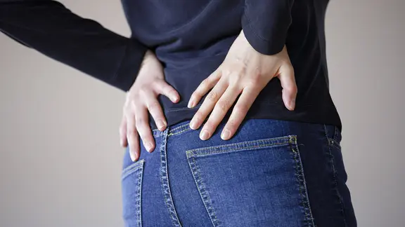 Eine Frau greift sich an den Rücken