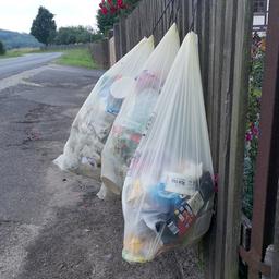 An einem Zaun hängen Müllsäcke.