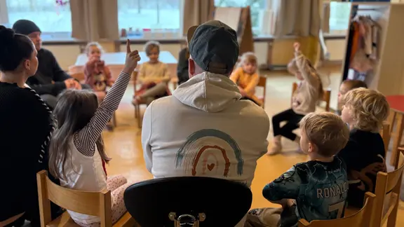 Des enfants et des enseignants sont assis en cercle. Des places en crèche sont supprimées.