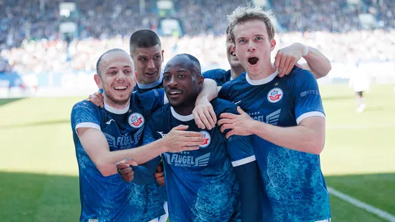 Rostock-Spieler bejubeln einen Treffer von Christian Kinsombi (M.)