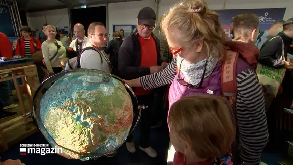 Eine Frau und ein Mädchen schauen sich einen Globus in einem Raum in Bremen an.