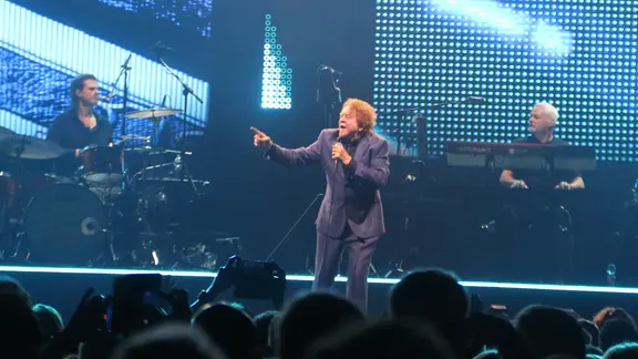 Ein Mann im Anzug singt auf einer Bühne in ein Mikrofon