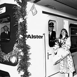 Ein blumengeschmückter S-Bahn-Zug mit Hamburg-Fahne. Helga Feddersen steht auf dem Bahnsteig, der Lokführer schaut aus der Tür.