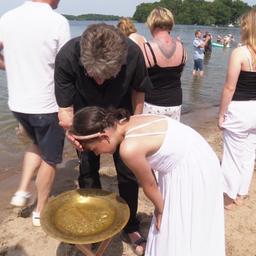 Ein Mädchen wird am Strand getauft.