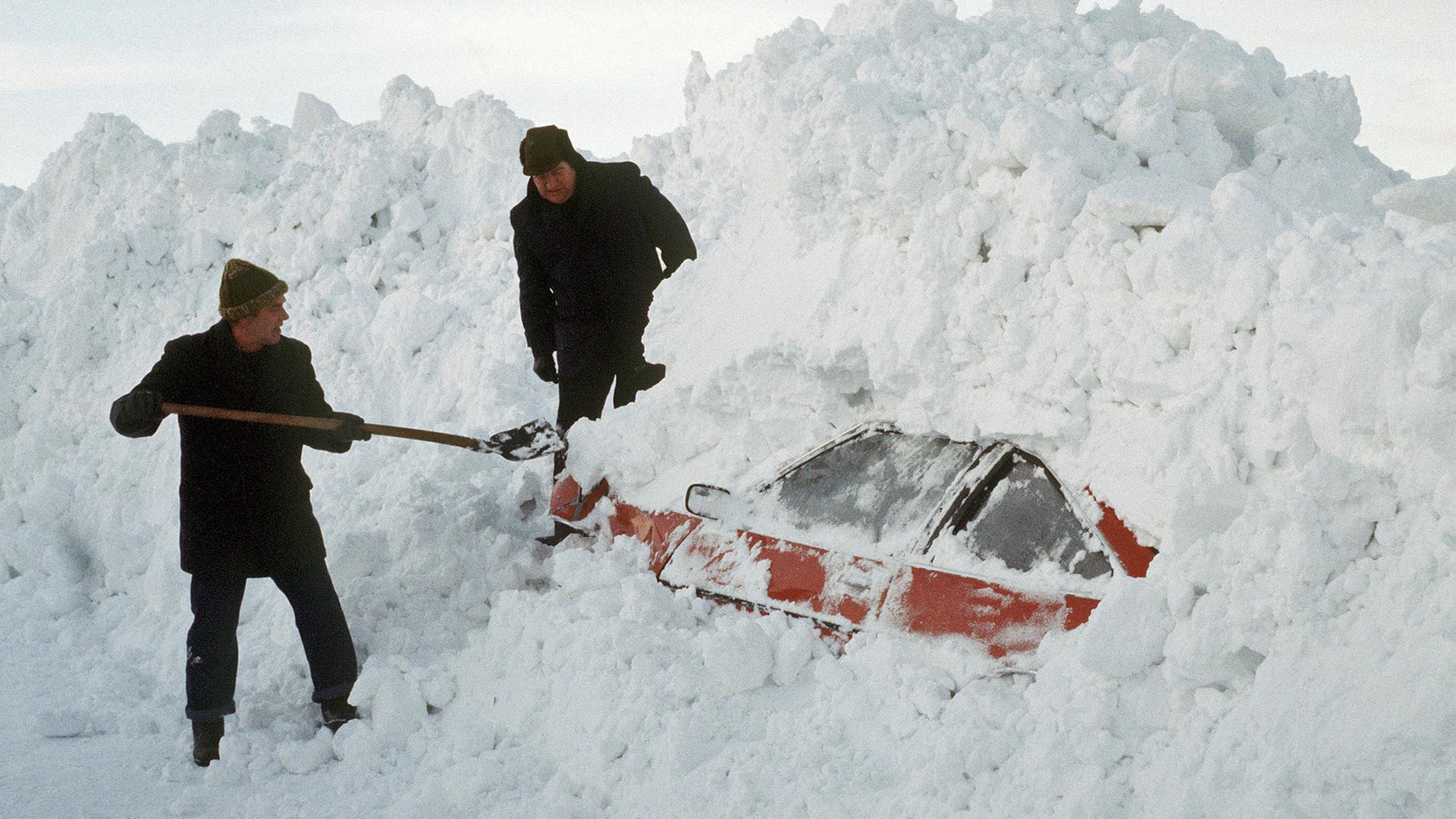 Zwei Männer graben mit einer Schaufel ein Auto aus den Schneemassen. Aufnahme vom Januar 1979. | picture-alliance / dpa, Spring