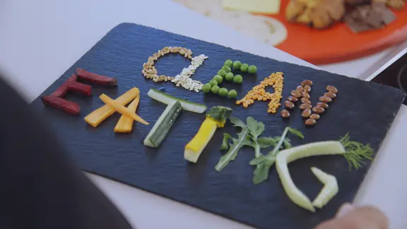 Gemüsestückchen auf einer Schiefertafel bilden Buchstaben und damit den Begriff "Clean Eating".
