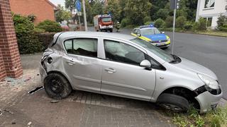 Das Auto steht mit Dellen und einem abgeknickten Reifen vor der Hauswand.