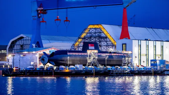 Ein geschmücktes U-Boot liegt vor einer Werft.