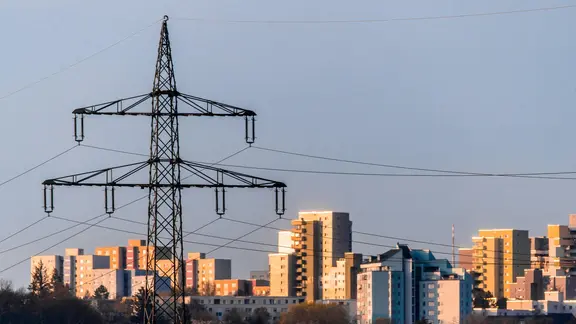 Ein Strommast steht vor Wohnhäusern