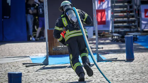 Ein Feuerwehrmann sprintet bei einer Firefighter Combat Challengemit einem Schlauch zum Brandort. (Themenbild)