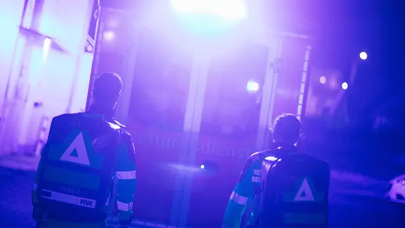 Rettungskräfte brachten den 22-Jährigen mit lebensgefährlichen Verletzungen ins Krankenhaus. (Themenbild) | NDR, Julius Matuschik Zwei Sanitäter rennen auf einen Krankenwagen zu, der sie mit blauen Lichtern anstrahlt.