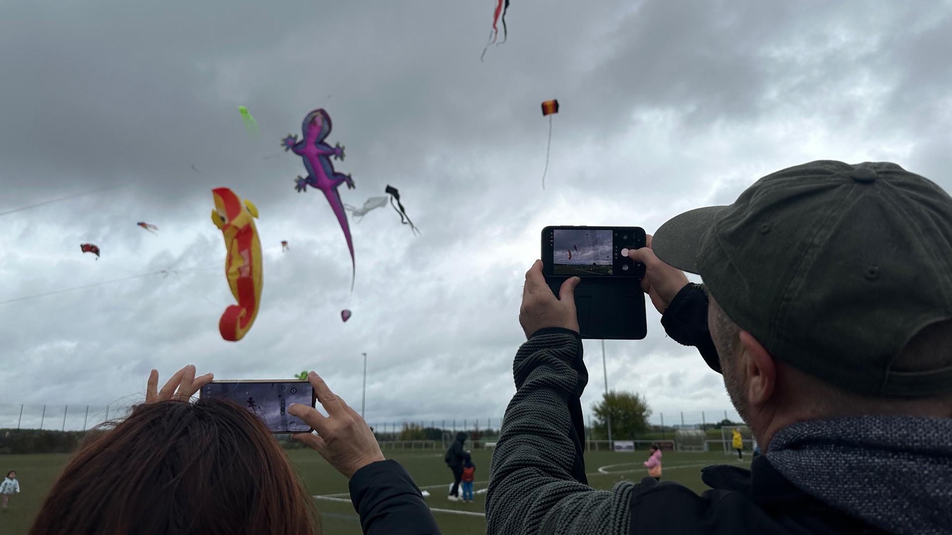 Zwei Menschen fotografieren Drachen am Himmel. | NDR