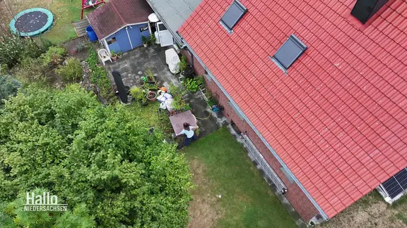 Blick von oben auf ein Wohnhaus mit Ziegeldach und den angrenzdenen grünen Garten mit Terasse