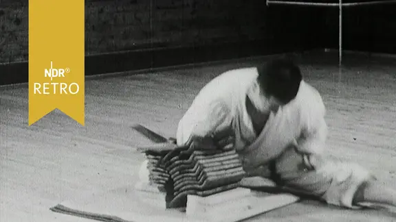 Ein Karatekämpfer zerschlägt bei einer Präsentation zehn übereinander liegende Dachziegel (1965)