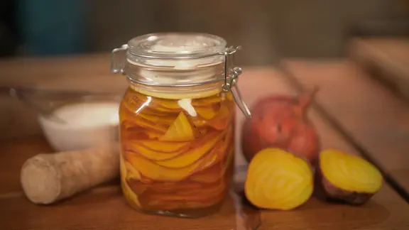 Ein Einmachglas mit mit gelber Bete steht auf einem Tisch.