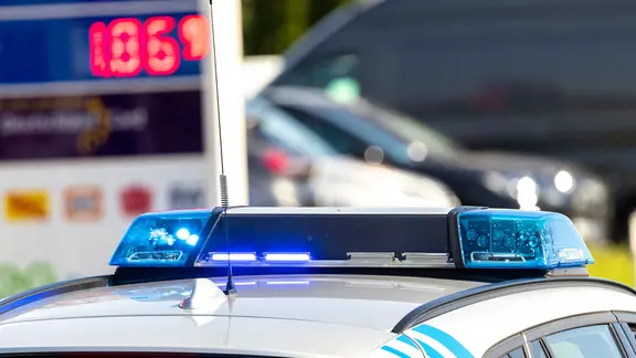 Ein Polizeiauto steht vor einer Tankstelle.