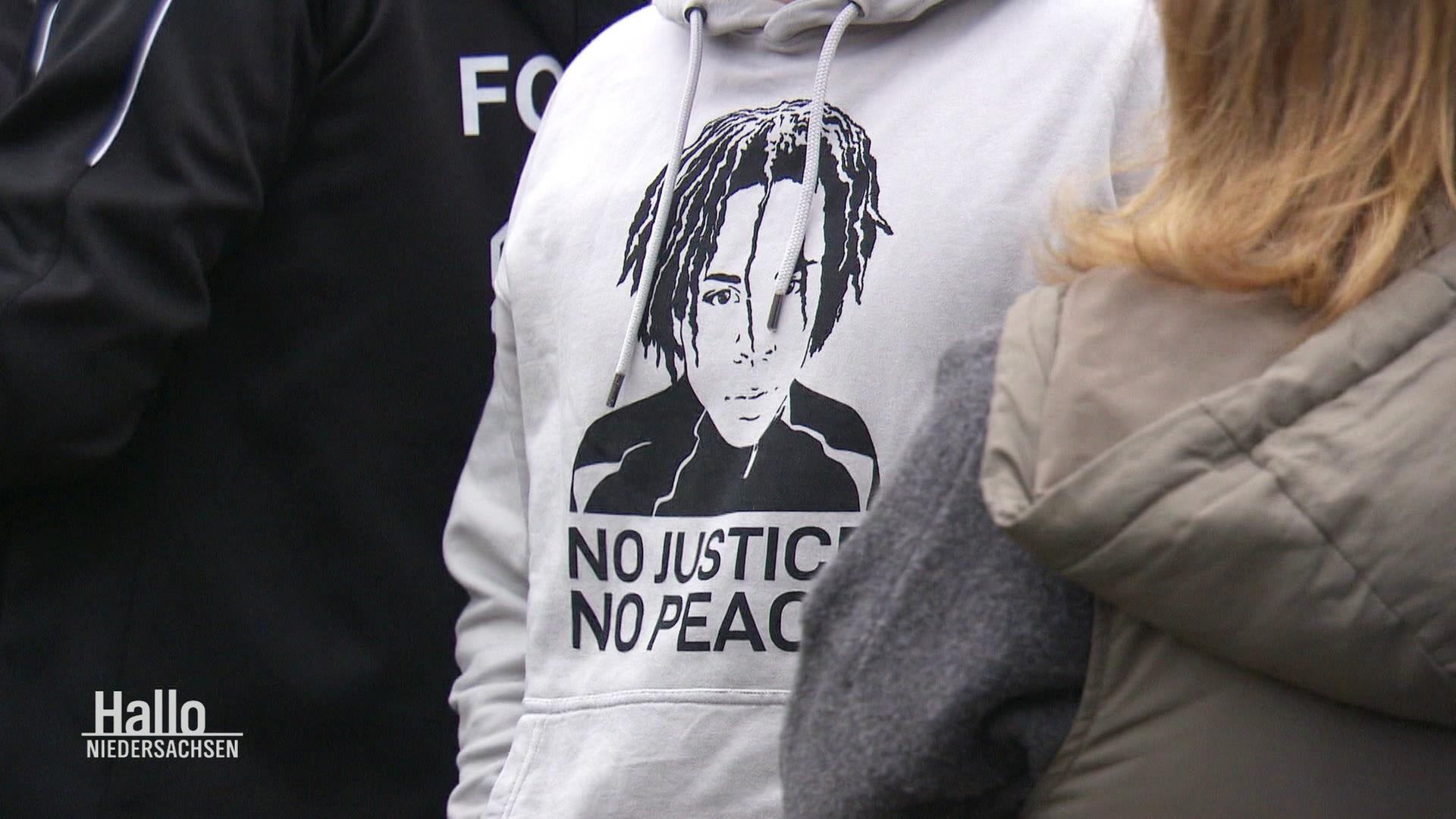 Auf einem Hoodie mit Bild von Lorenz A. steht NO JUSTICE NO PEACE. | Screenshot