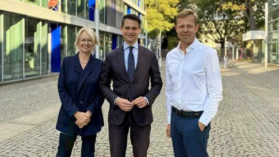 Eine Frau und zwei Männer lächeln in die Kamera